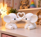 White pair of elephants with trunks forming a heart in a nursery