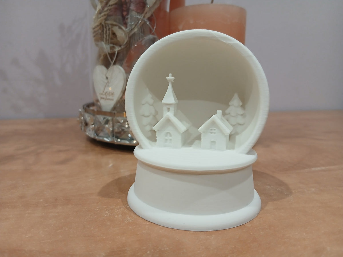 Christmas village with church, house and fir trees in a snow globe frame