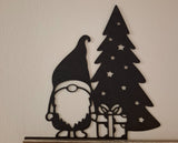 Christmas gnome figure with a present by the Christmas tree