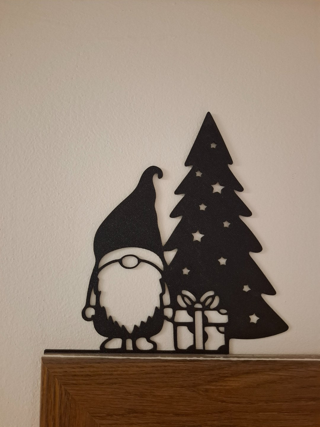 Christmas gnome figure with a present by the Christmas tree