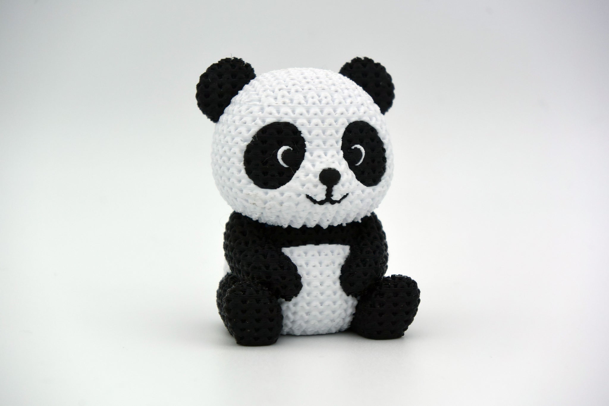 Close-up of a knitted panda figurine showing black and white crochet-look texture, small decorative object