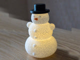 Snowman with hat and nose over an LED tealight