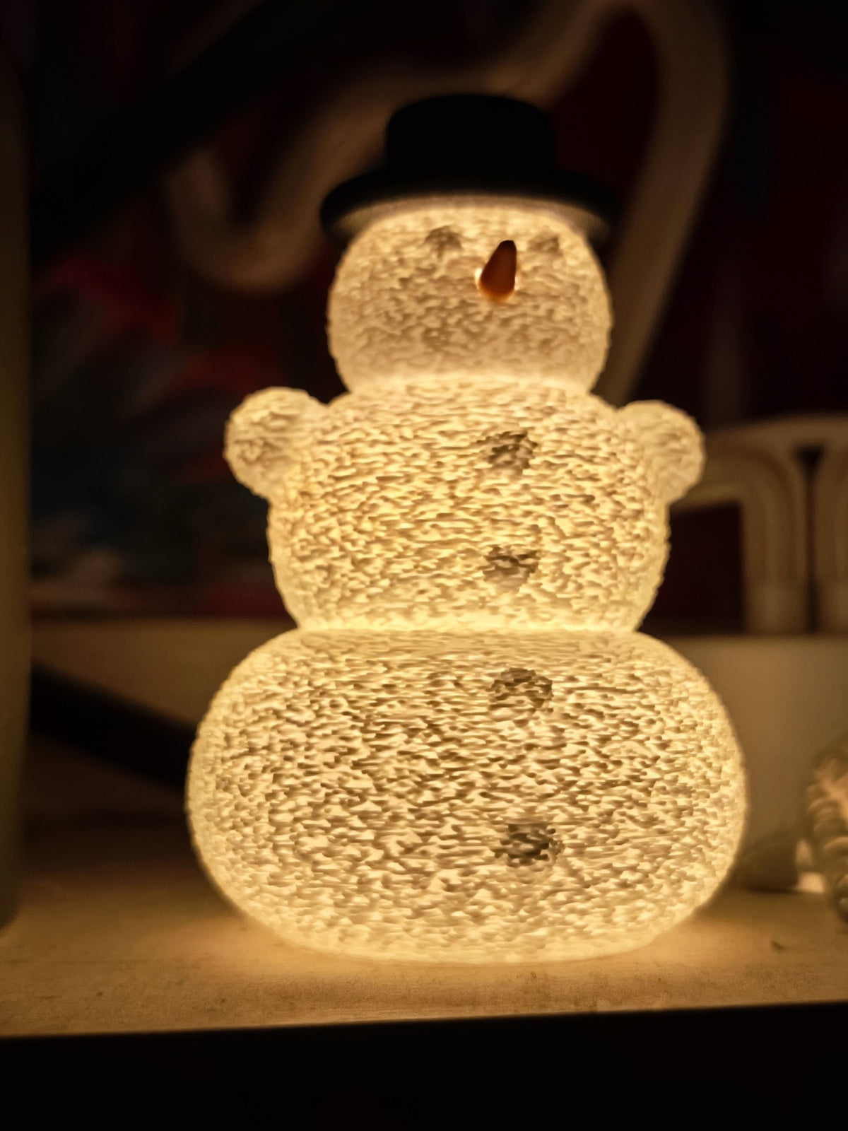 Snowman with hat and nose over an LED tealight